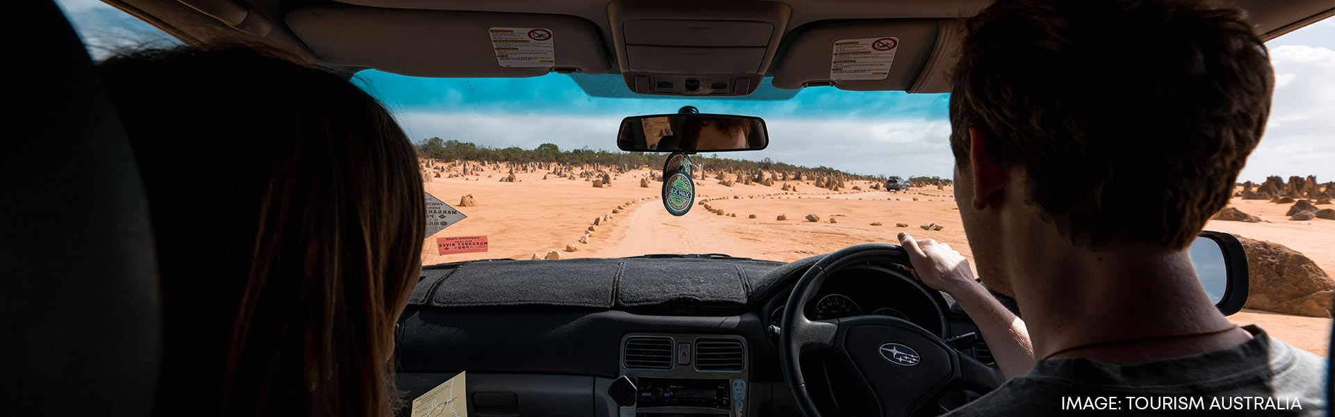 Couple driving across Australian in rental car