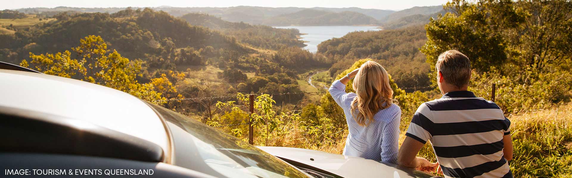 Couple leaning against rental car admiring view